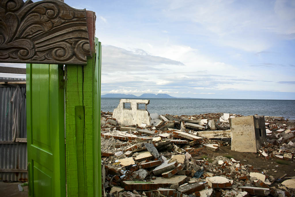 Tsunami ruins contrast with the door of a public shower built by residents. One year after 2004 December 26 tsunami reportage. Banda Aceh, Aceh province, Sumatra, Indonesia.
